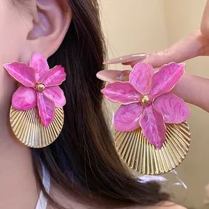 Detail shot of pink enamel flower earrings with gold pleated texture on a model