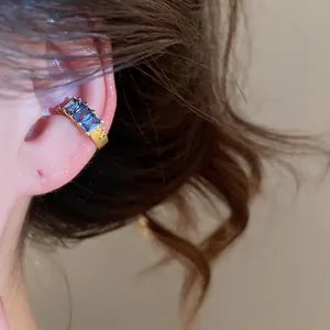 Close-up detail of a gold-plated ear cuff featuring three rectangular blue zircons