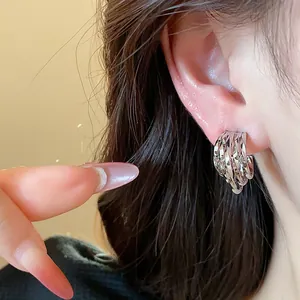 Macro view of minimalist silver C-shaped earrings with elegant twisted metal layers
