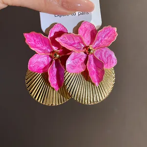 Close-up of pink flower drip oil earrings with pleated gold semicircular metal disks