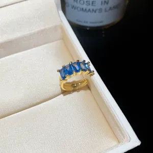 Close-up view of gold-plated ear cuff with four rectangular blue zircons in a jewelry box.