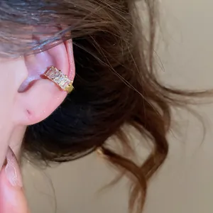 Close-up of 18k gold plated ear cuff with three rectangular zircons worn on ear