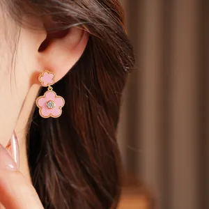Detailansicht der vergoldeten rosa Blumenohrringe mit Zirkonia am Ohr eines Modells