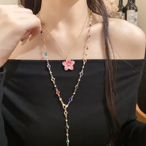 Detail shot of a layered gold necklace featuring crystal beads and pink flower pendant