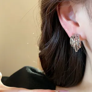 Detailed view of elegant layered C-shaped silver hoop earrings on a model ear