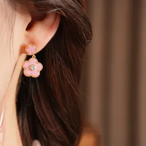 Nahaufnahme vergoldeter rosa Blumenohrringe mit Zirkon am Ohr des Modells im Detail