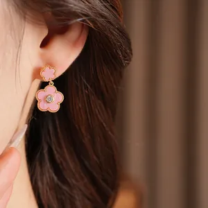 Detailaufnahme eleganter rosa Blumenohrringe mit Vergoldung und Zirkon, getragen von einem Modell