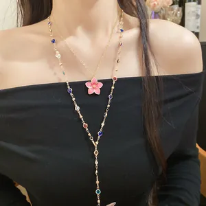 Detailed view of a layered gold necklace with a pink flower pendant and colorful beads.