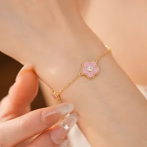 Nahaufnahme eines vergoldeten Armbands mit rosa Blume am Handgelenk