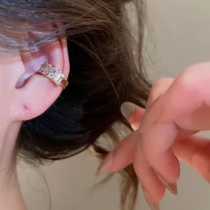 Detailed view of a gold-plated ear cuff with sparkling square zircons worn on the ear