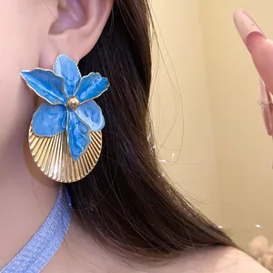 Close-up view of elegant blue enamel flower earrings featuring a golden pleated texture