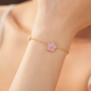 Nahaufnahme eines vergoldeten Armbands mit rosa Blumenanhängern und Zirkonia-Steinen