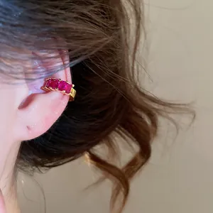 Detail view of 18k gold plated ear cuff featuring three radiant square red zircons on ear.