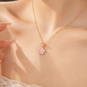 Nahaufnahme einer eleganten vergoldeten Kette mit zwei rosa Blumenanhängern und Zirkon.