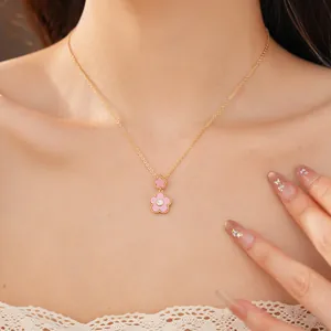 Detailansicht einer vergoldeten Halskette mit rosa Blumenanhängern und einem Zirkon