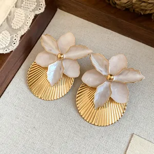 Detail view of sweet white enamel flower earrings featuring a gold pleated texture.