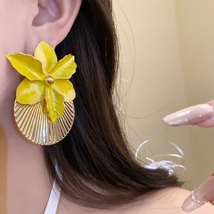 Close-up detail of oversized yellow enamel flower earrings with gold-tone pleated disk texture