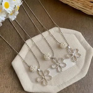 Close-up of silver hollow flower pendants with ivory pearls on delicate bead chains.
