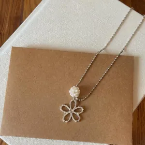 Detail shot of a French minimalist openwork flower necklace with a pearl pendant