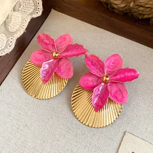 Detail of pink flower earrings with gold pleated fan base for vacation style.