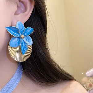 Detailed macro shot of blue enamel flower earrings with a gold pleated texture finish