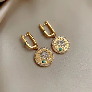 Macro detail of 18K gold plated earrings with cubic zirconia and turquoise