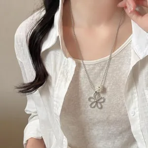Detail shot of a delicate silver hollow flower necklace with a pearl bead on a model's neck