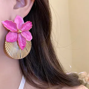 Detailed close-up of vibrant pink flower earrings with gold pleated fan texture design.