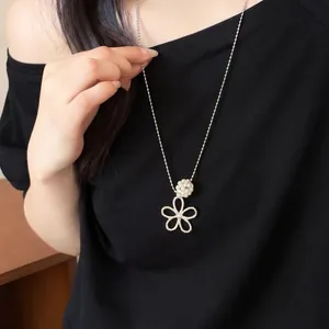 Detail view of a French hollow flower pearl necklace on a model wearing a black shirt