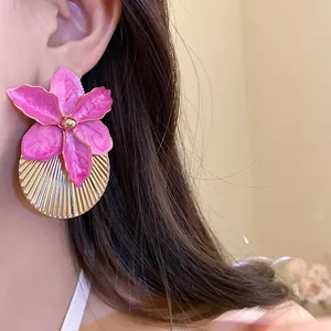 Close-up of elegant pink orchid flower earrings with golden pleated disc detail on model