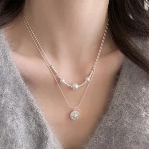 Detail view of a double layered necklace with pearl beads and a zircon star pendant on model