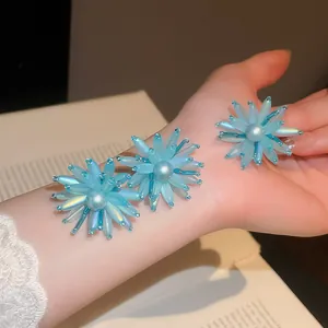 Detaillierte Ansicht des blauen Acryl-Blumen- und Perlen-Accessoire-Sets am Arm