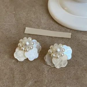 Primer plano de elegantes pendientes de perlas blancas de estilo francés con pétalos de flores.