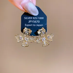 Primo piano dettagliato degli orecchini a perno a farfalla in zircone su cartoncino nero.