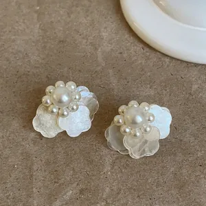 Primer plano de elegantes pendientes de pétalos de flores de perlas blancas con brillo.