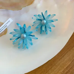 Detailaufnahme blauer Blumen-Ohrstecker aus Acryl mit Perle und Perlenblütenblättern.
