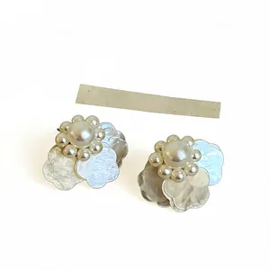 Pendientes de perlas con pétalos de flores de estilo francés sobre un fondo blanco limpio.