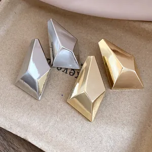 Close-up of geometric faceted stud earrings in polished gold and silver finishes