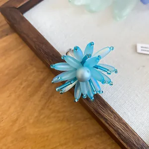Detailansicht eines blauen Acryl-Blumenrings im Sommer-Stil mit einer Perle in der Mitte