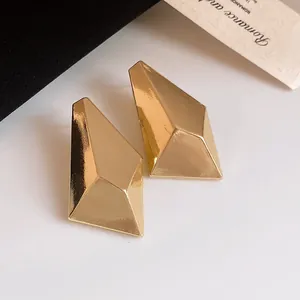Close-up of vintage minimalist gold geometric faceted stud earrings with metallic finish