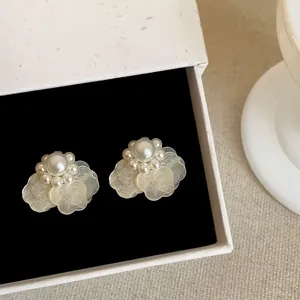 Primer plano de pendientes de flores de estilo francés con perlas blancas y pétalos.
