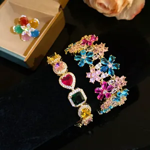 Close-up detail of vibrant colorful zircon flower bracelets and ring set on black velvet.