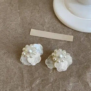 Primer plano de elegantes pendientes de pétalos blancos de estilo francés con perla