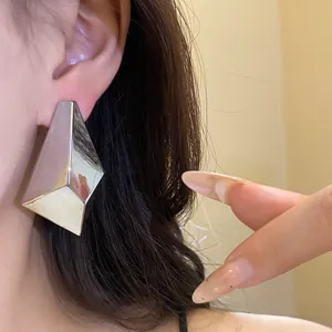 Detailed close-up of a vintage minimalist silver geometric multifaceted stud earring on ear