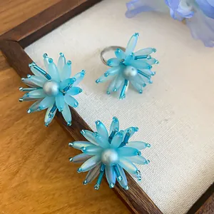 Detailansicht der hellblauen Acryl-Blumen-Ohrringe und des Ringsatzes