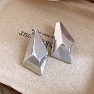 Macro view of minimalist silver geometric faceted stud earrings with a glossy finish