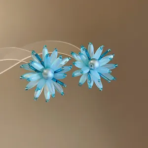 Detaillierte Makroaufnahme blauer Acryl-Blumenohrstecker mit zentralen Perlenperlen