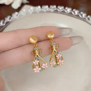 Dettaglio ravvicinato di orecchini Pipa dorati con fiori in smalto rosa e zircone brillante