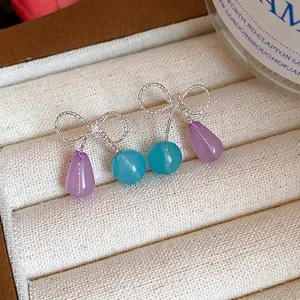 Eleganti orecchini a fiocco in argento con perle di resina colorata in un portagioie