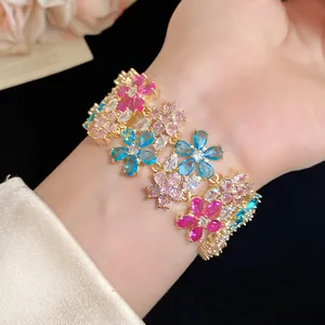 Elegant gold-plated bracelet with vibrant zircon flower charms on a wrist.